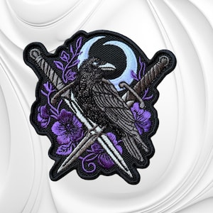 May include: An embroidered patch featuring a black raven perched in front of a light blue crescent moon. Two crossed silver swords are positioned behind the bird, surrounded by purple flowers and thin green vines on a black background.