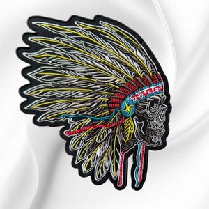 May include: An embroidered patch featuring a skull wearing a large feathered headdress. The design uses black, white, yellow, red, and blue thread. The skull is shown in profile, and the headdress features detailed feather patterns and a band.