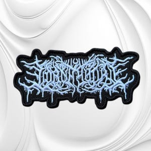 May include: A rectangular embroidered patch featuring a black background with intricate, light blue, stylized lettering that resembles tangled, dripping branches or roots. The design has a thick black border and a textured, fabric-like appearance.