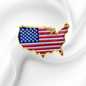 May include: An embroidered patch in the shape of the contiguous United States map. The design features the American flag pattern with a blue field of white stars on the left and horizontal red and white stripes, all outlined in gold thread.