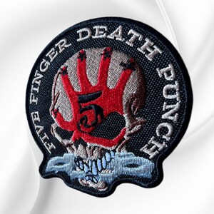 May include: A circular embroidered patch featuring a skull design with a red handprint over the eye sockets and a black number five in the center. The text Five Finger Death Punch is stitched in white along the black border, with light blue teeth.
