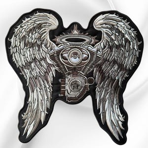 May include: A large embroidered patch featuring a central motorcycle engine block topped with a halo, flanked by two expansive, detailed feathered wings. The design uses shades of silver, grey, and brown thread on a solid black fabric background.