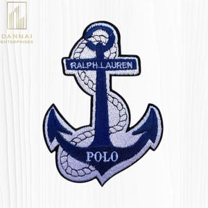 May include: Embroidered patch featuring a navy blue anchor design with white rope detailing. The patch includes the text "RALPH LAUREN" and "POLO" in white lettering. The anchor is set against a white background.