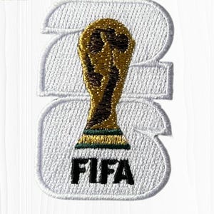 May include: Embroidered patch featuring a gold trophy, the FIFA World Cup, centered on a white background. The patch is in the shape of the number 23, with the word "FIFA" in black letters at the bottom. The patch has a white stitched border.