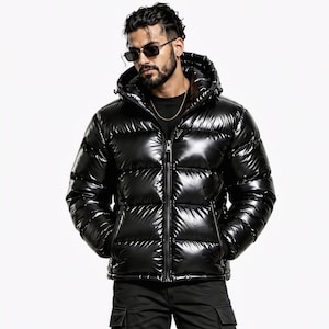 Puede incluir: Una chaqueta acolchada negra con un acabado brillante y reflectante, que presenta una cremallera frontal completa, una capucha y paneles acolchados horizontales. La chaqueta tiene mangas largas y dos bolsillos laterales con cremallera.