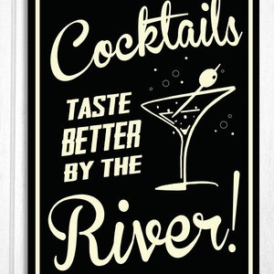 May include: Black and white sign with the text "Cocktails Taste Better By The River!" in a retro font. A martini glass with an olive is pictured next to the text.