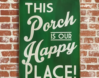 Op de afbeelding: Een groen houten bord met witte tekst die "This Porch is Our Happy Place!" zegt.