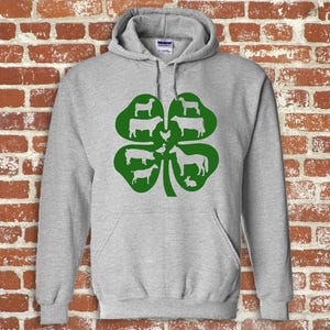 May include: A gray hooded sweatshirt with a green four-leaf clover design. The clover has white silhouettes of farm animals, including a cow, pig, horse, goat, chicken, and rabbit.
