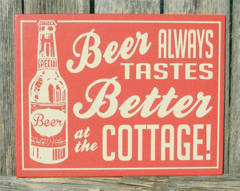May include: Red wooden sign with white text that reads "Beer Always Tastes Better at the Cottage!"  A white outline of a beer bottle is on the left side of the sign.