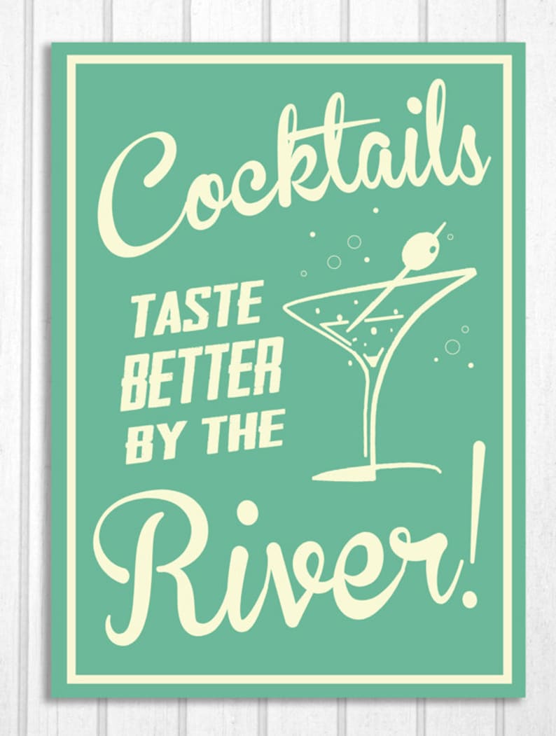 May include: A teal green sign with white text that reads "Cocktails Taste Better By The River!" with a white martini glass illustration.