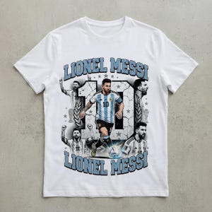 K&ouml;nnte beinhalten: Ein wei&szlig;es Kurzarm-T-Shirt mit einem Grafikdruck von Lionel Messi. Das Design enth&auml;lt den Text LIONEL MESSI, eine gro&szlig;e Nummer 10 und mehrere Bilder des Sportlers im argentinischen Fu&szlig;balltrikot sowie eine Grafik eines Fu&szlig;balls.