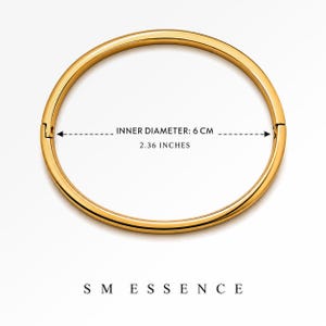 May include: A gold-colored bangle bracelet with a clasp closure. The inner diameter is 2.36 inches (6 cm). The bracelet is circular and sits on a white background. The brand name "SMESSENCE" is at the bottom.