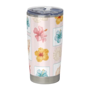 Puede incluir: Un vaso de viaje de acero inoxidable con tapa transparente. El vaso presenta un fondo rosa claro con un patrón de coloridas flores de hibisco y conchas marinas en cuadrados blancos. Las flores son rosas, amarillas y turquesas.