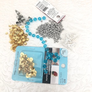 May include: An assortment of jewelry-making supplies, including gold-colored thumbtacks, silver-colored beads, blue crystal beads, and earring posts. The earring posts are 0.31 inches or 8 mm. The packaging reads "Nickel Free".