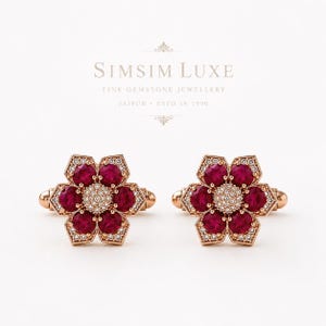 May include: A pair of rose gold cufflinks featuring a flower-shaped design with six round, deep red rubies surrounding a central cluster of tiny white diamonds. The text SIMSIM LUXE FINE GEMSTONE JEWELLERY JAIPUR ESTD IN 1990 is visible above.