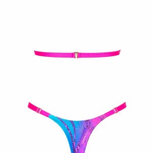 May include: A two-piece lingerie set featuring a bright hot pink halter neck strap and a matching horizontal back strap with gold-tone hardware. The thong-style bottom features a vibrant blue and purple gradient pattern with a dark snakeskin print.
