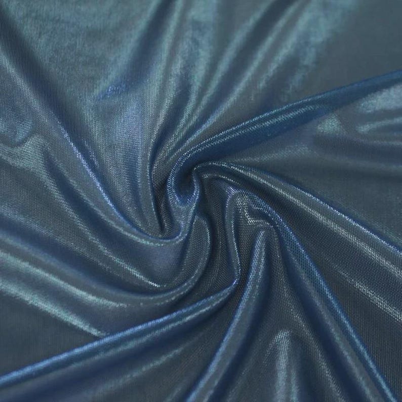 May include: A piece of fabric with a deep blue hue and a metallic, shimmering finish. The material is gathered in the centre, creating soft, flowing folds and highlights that emphasise the reflective, glossy texture of the textile surface.