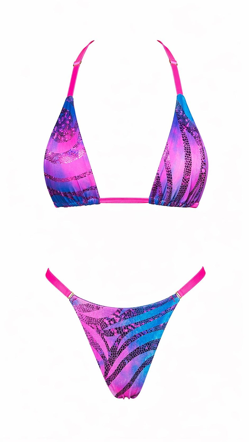May include: A two-piece bikini set featuring a vibrant pink and blue tie-dye pattern with a dark snakeskin print overlay. The top has triangle cups with bright pink adjustable straps, and the bottom is a high-cut style with pink side straps.