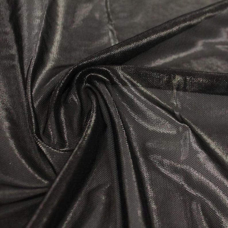 May include: A piece of black fabric with a subtle sheen and a fine, mesh-like texture. The material is draped to create soft folds and highlights, showcasing the reflective quality of the surface and the intricate, uniform weave of the textile.