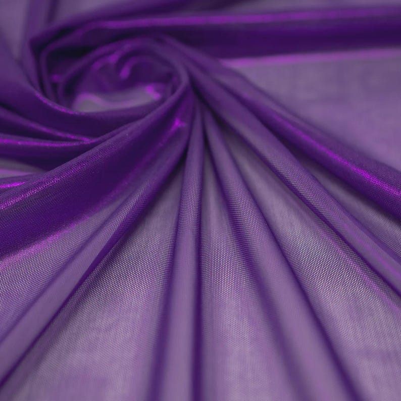 May include: A sheer, deep purple fabric with a fine mesh texture. The material is draped in soft, flowing folds that create a swirling pattern, highlighting the translucent quality and the vibrant, saturated violet hue of the textile surface.