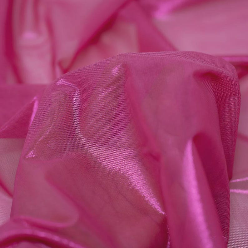 May include: A vibrant hot pink fabric with a semi-sheer, lightweight texture. The material features a subtle metallic sheen that catches the light, creating soft folds and ripples across the surface of the translucent, fine-knit textile.