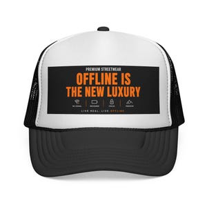 Peut inclure: Casquette de camionneur noire et blanche avec une visière incurvée. Le panneau avant affiche le texte "OFFLINE IS THE NEW LUXURY" en orange et blanc. La casquette comprend également le texte "PREMIUM STREETWEAR".