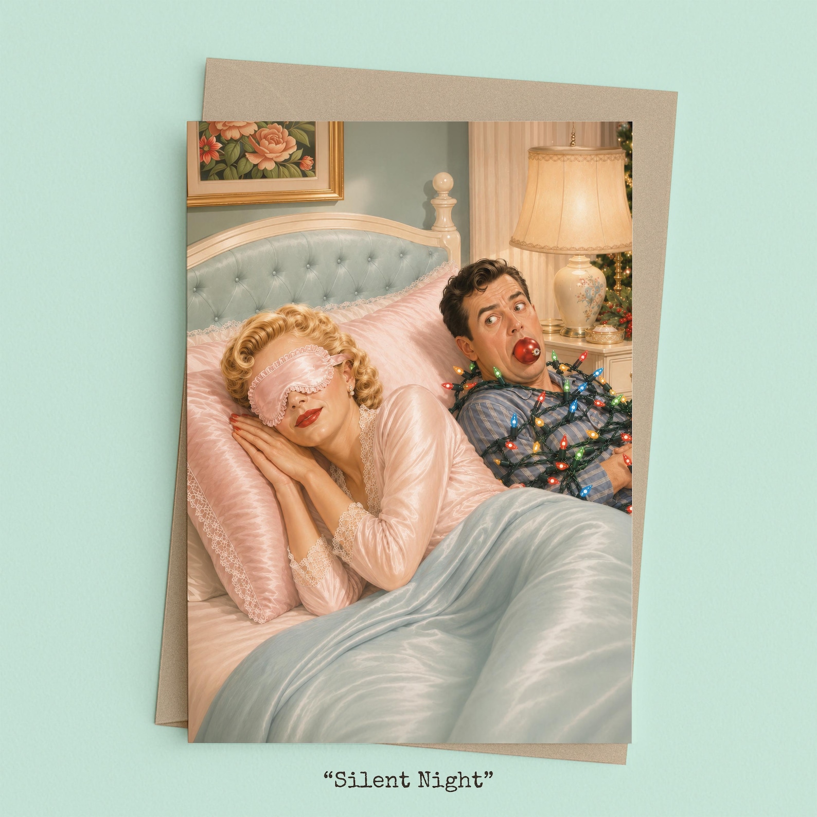 Woman sleeping soundly in bed while her husband sits tangled in Christmas lights with an ornament in his mouth