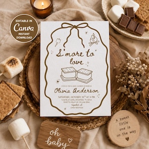 May include: A white rectangular baby shower invitation card with a brown scalloped border and a bow at the top. The text reads S'more to love, Olivia Anderson, Saturday, October 15th at 3 PM, 1234 Blue Lane, Houston, TX 12345-67890.