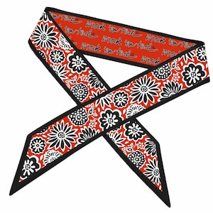 Pode incluir: Um lenço longo e estreito com um fundo vermelho vibrante e um padrão floral repetitivo em preto e branco. O verso é vermelho sólido com o texto preto "wreck 'em tech" impresso repetidamente em letra cursiva por todo o tecido.