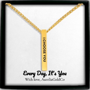 Peut inclure: Un collier pendentif barre verticale doré avec le texte gravé I CHOOSE YOU. La carte de présentation sous le pendentif porte le texte imprimé Every Day, It's You et With love, AureliaGoldCo en polices script et serif noires.