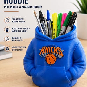 May include: A blue pen holder shaped like a hoodie, featuring the New York Knicks logo. The holder is filled with pens and markers. Text on the holder reads "NY Knicks Hoodie, Pen, Pencil & Marker Holder."