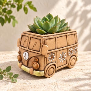 May include: A tan-colored ceramic planter shaped like a vintage van with a peace sign on the front, white daisy flower decals on the side, and a green succulent plant growing out of the top. The planter features molded headlights and bumpers.