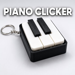以下が含まれることがあります： PIANO CLICKERという文字が入った白黒のピアノ鍵盤型クリッカーキーホルダー。黒い長方形のベースに3つの白い鍵盤と2つの盛り上がった黒い鍵盤があり、短いチェーンで銀色の金属製リングに取り付けられています。