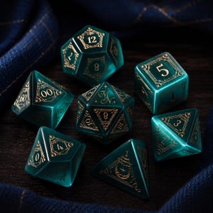 May include: A set of seven polyhedral dice in a translucent deep teal colour. Each die features intricate gold-coloured line art designs, including celestial motifs and geometric frames around the numbers. The set includes various shapes.