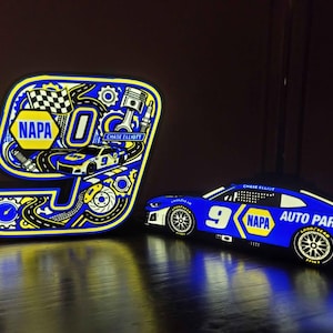 May include: A glowing LED sign shaped like the number 9, featuring NAPA branding, a race car, and automotive parts, alongside a separate illuminated blue race car model with the number 9, NAPA logo, and the text Chase Elliott Auto Parts.