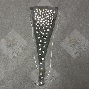 May include: A black triangular garment featuring a dense arrangement of clear, reflective rhinestones across the front surface. The piece includes thin, transparent elastic straps attached to the sides, designed to secure the item in place.