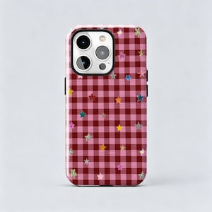 May include: A smartphone case featuring a dark red and light pink gingham plaid pattern. The surface is decorated with numerous small, multi-coloured stars in various shades of yellow, blue, pink, and silver, scattered across the checkered design.