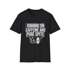 Peut inclure: Un t-shirt noir à manches courtes avec une impression graphique blanche vieillie. Le texte indique RUNNING ON CAFFEINE AND PURE SPITE au-dessus d'une petite illustration d'une silhouette à capuche et d'une canette avec un éclair.