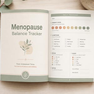 Könnte beinhalten: Ein offenes Journal mit dem Titel "Menopause Balance Tracker" mit täglichen Tracking-Seiten. Die linke Seite zeigt Text und eine botanische Illustration. Die rechte Seite enthält Abschnitte für Energieniveau, Symptome, Stimmung und Schlaf, mit einem Stift in der Nähe.