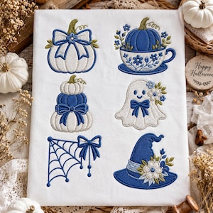Op de afbeelding: Een wit stoffen paneel met zes geborduurde ontwerpen in blauw en wit: een pompoen met een strik, een pompoen in een bloemrijk theekopje, een stapel pompoenen, een lachend spookje met bloemen, een spinnenweb met een strik en een heksenhoed met bloemen.