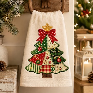 Puede incluir: Una toalla de mano color crema con un gran diseño de árbol de Navidad bordado. El árbol está compuesto por varios parches de tela en rojo, verde y blanco con patrones de lunares, cuadros y flores, rematado con una estrella dorada y un lazo rojo.