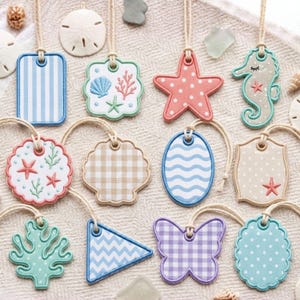 May include: A collection of twelve decorative hanging tags in various shapes including rectangles, stars, seahorses, shells, and butterflies. The tags feature patterns like stripes, gingham, polka dots, and waves in pastel colors with nautical motifs.