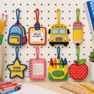 May include: Eight embroidered school-themed bag tags with loops. Designs include a blue backpack, a name tag with 'HELLO MY NAME IS', a yellow school bus, a pencil, a star with 'STAR STUDENT', a pink notebook, a crayon box, and a red apple.