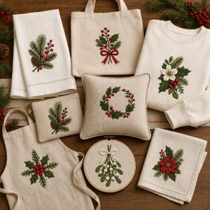 Puede incluir: Una colección de artículos textiles de color crema con motivos navideños bordados que incluyen ramas de pino, acebo, muérdago y flores de pascua. El conjunto incluye una bolsa de tela, sudadera, delantal, cojín, estuche con cremallera y dos paños.