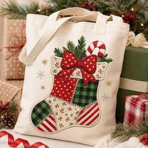 Puede incluir: Un bolso de tela color crema con un diseño bordado de calcetín navideño de estilo patchwork. El calcetín muestra lunares rojos, cuadros verdes y negros, rayas rojas y blancas, y motivos florales, rematado con un lazo rojo decorativo.