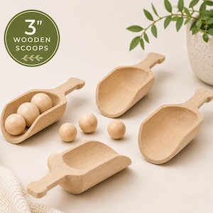 May include: Three light-colored wooden scoops measuring 3 inches in length, accompanied by five small wooden spheres. The scoops have a smooth, natural finish and a short handle. A circular graphic in the corner displays the text 3" WOODEN SCOOPS.