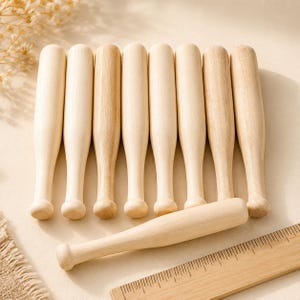 May include: A collection of eight light-colored wooden batons with smooth, cylindrical bodies and rounded ends. Seven batons are arranged vertically in a row, while one baton is placed horizontally in front, next to a wooden ruler showing inches.