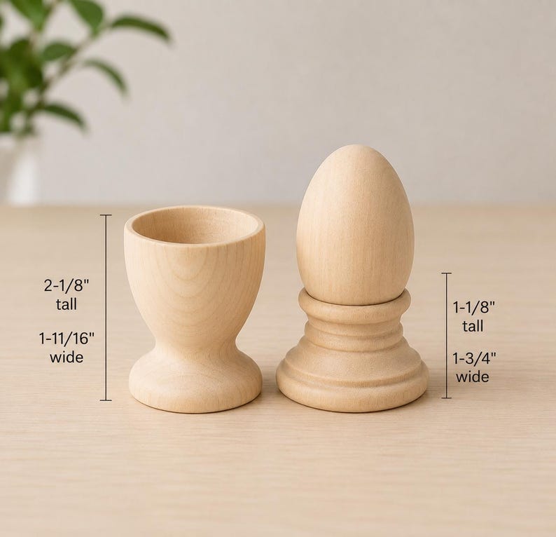 May include: A light-colored wooden egg cup and a wooden egg on a stand. The egg cup is 2-1/8 inches tall and 1-11/16 inches wide. The egg on the stand is 1-1/8 inches tall and 1-3/4 inches wide. Both items have a smooth, natural wood grain finish.