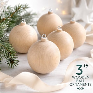 May include: A set of four smooth, light-colored wooden ball ornaments, each featuring a silver metal eyelet at the top for hanging. The text 3" WOODEN BALL ORNAMENTS is printed in the lower right corner of the image.