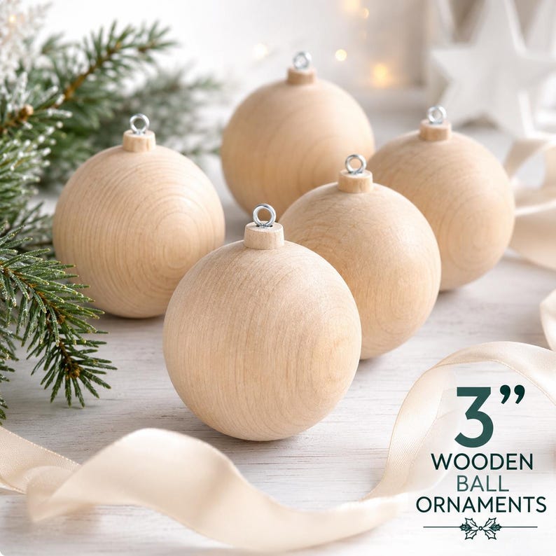 May include: A set of four smooth, light-colored wooden ball ornaments, each featuring a silver metal eyelet at the top for hanging. The text 3" WOODEN BALL ORNAMENTS is printed in the lower right corner of the image.
